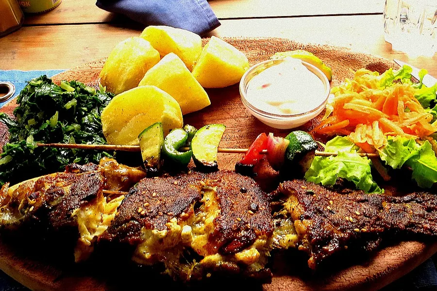 A grilled trout served with potatoes and greens